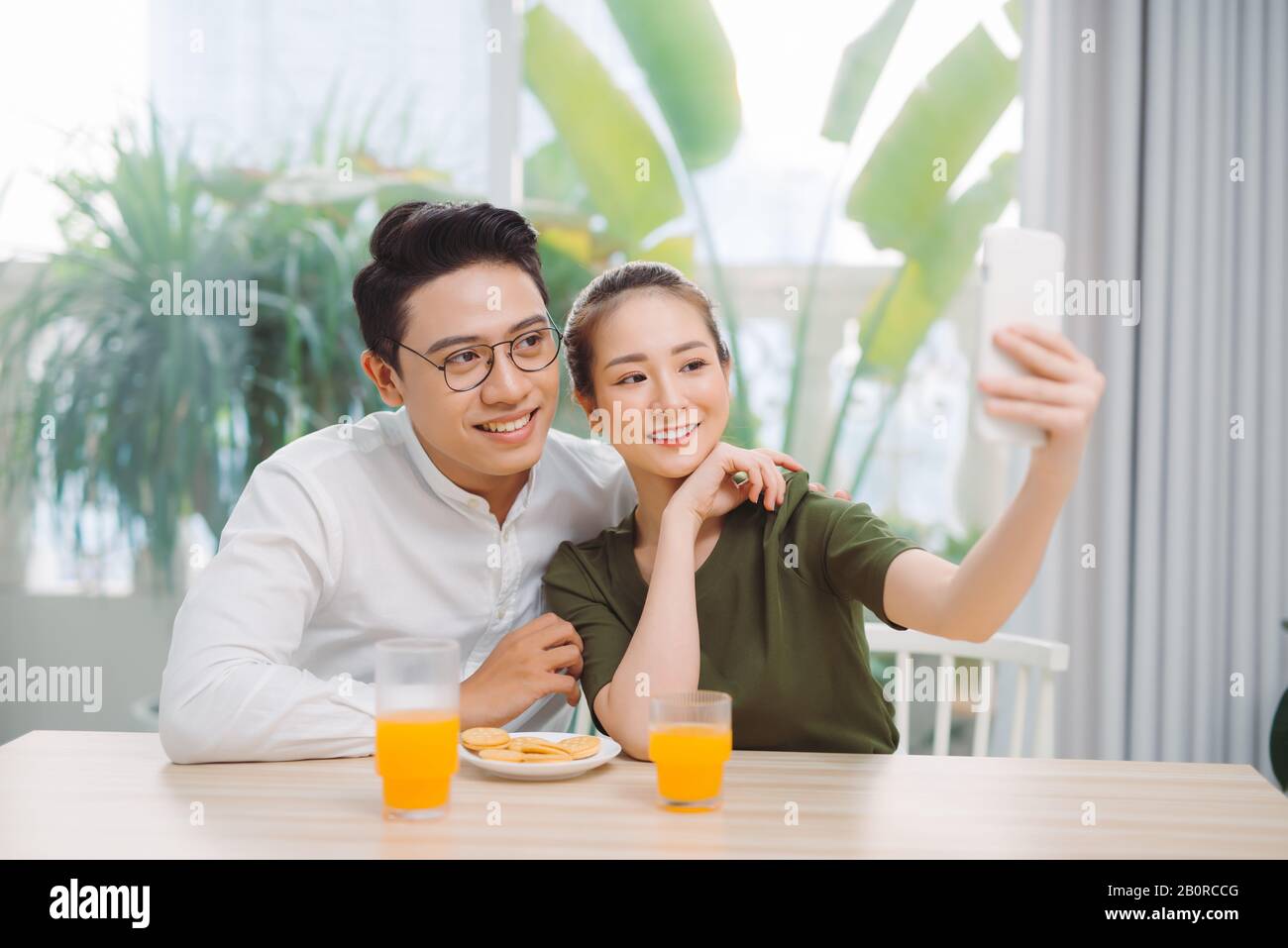 Beautiful young couple making selfie ,using a smart phone and smiling while sitting in their apartment Stock Photo