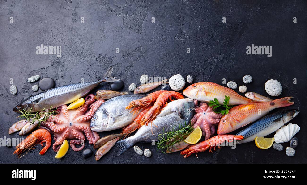 Fresh fish and seafood assortment on black slate background. Copy space