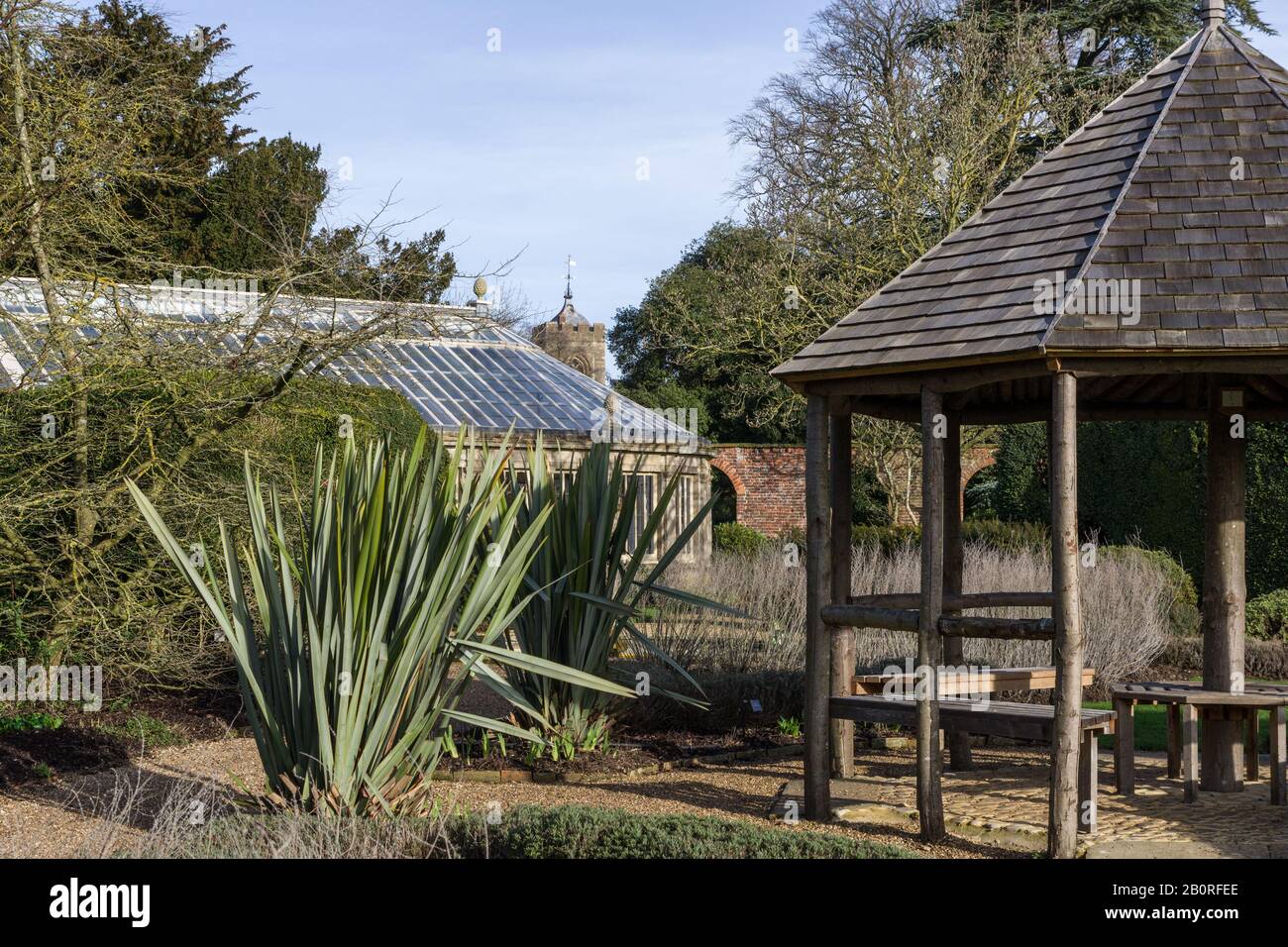 A cold but sunny Winter day at Castle Ashby Gardens, Northamptonshire, UK; pergola, greenhouse and a distant church tower Stock Photo