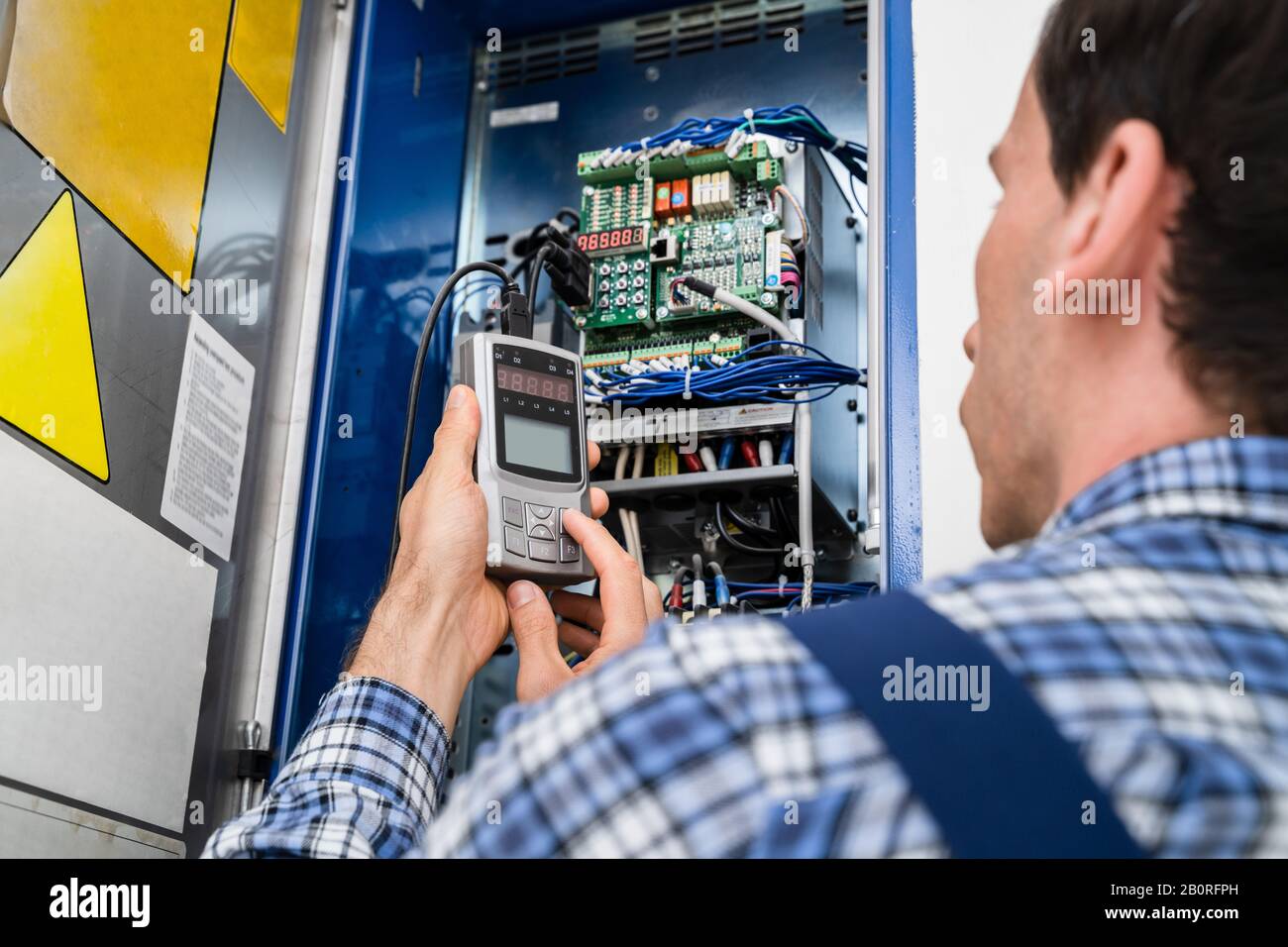 Photo Of Young Male Technician Examining Fusebox Stock Photo