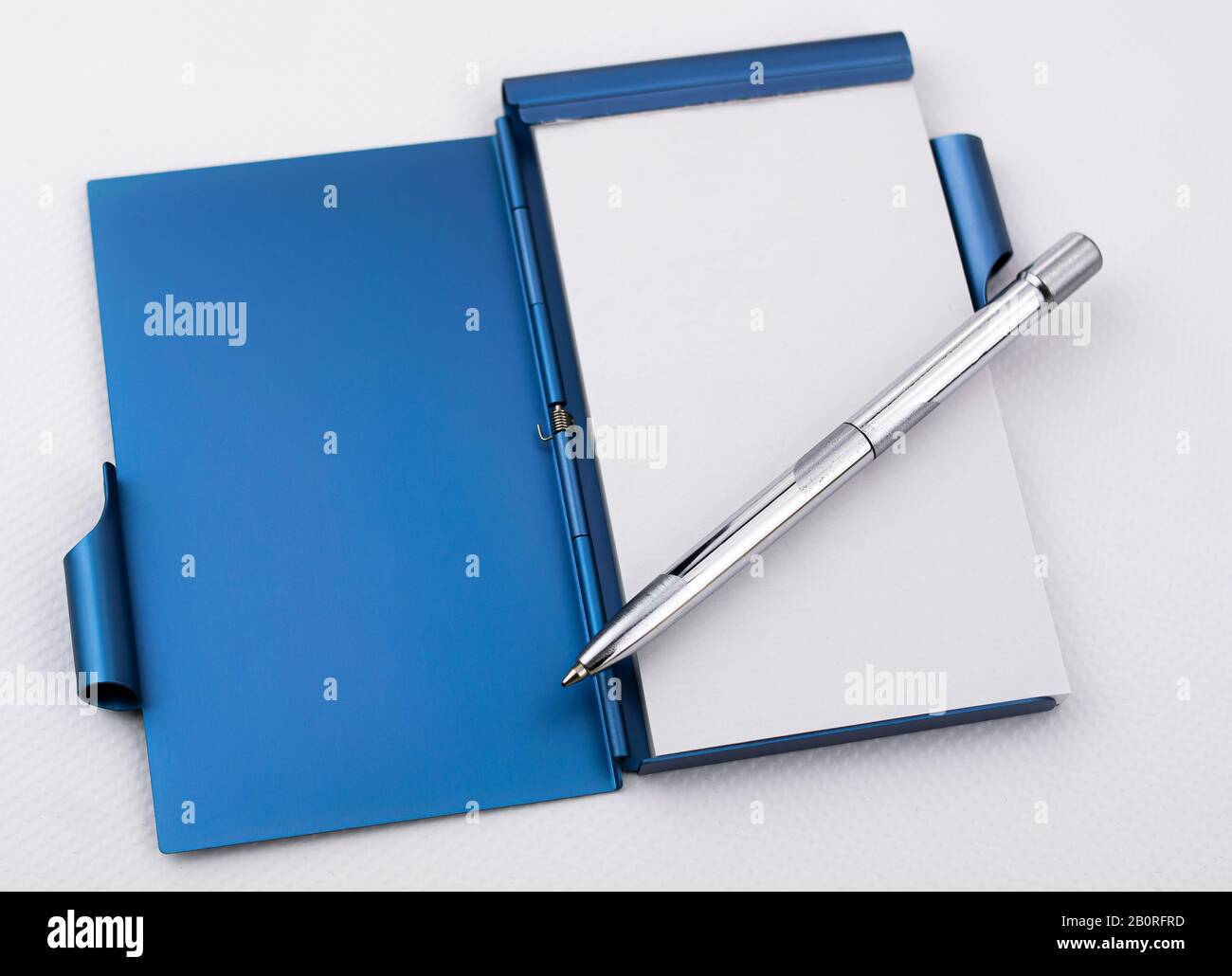 Open metallic notepad with white sheets and chrome pen Stock Photo