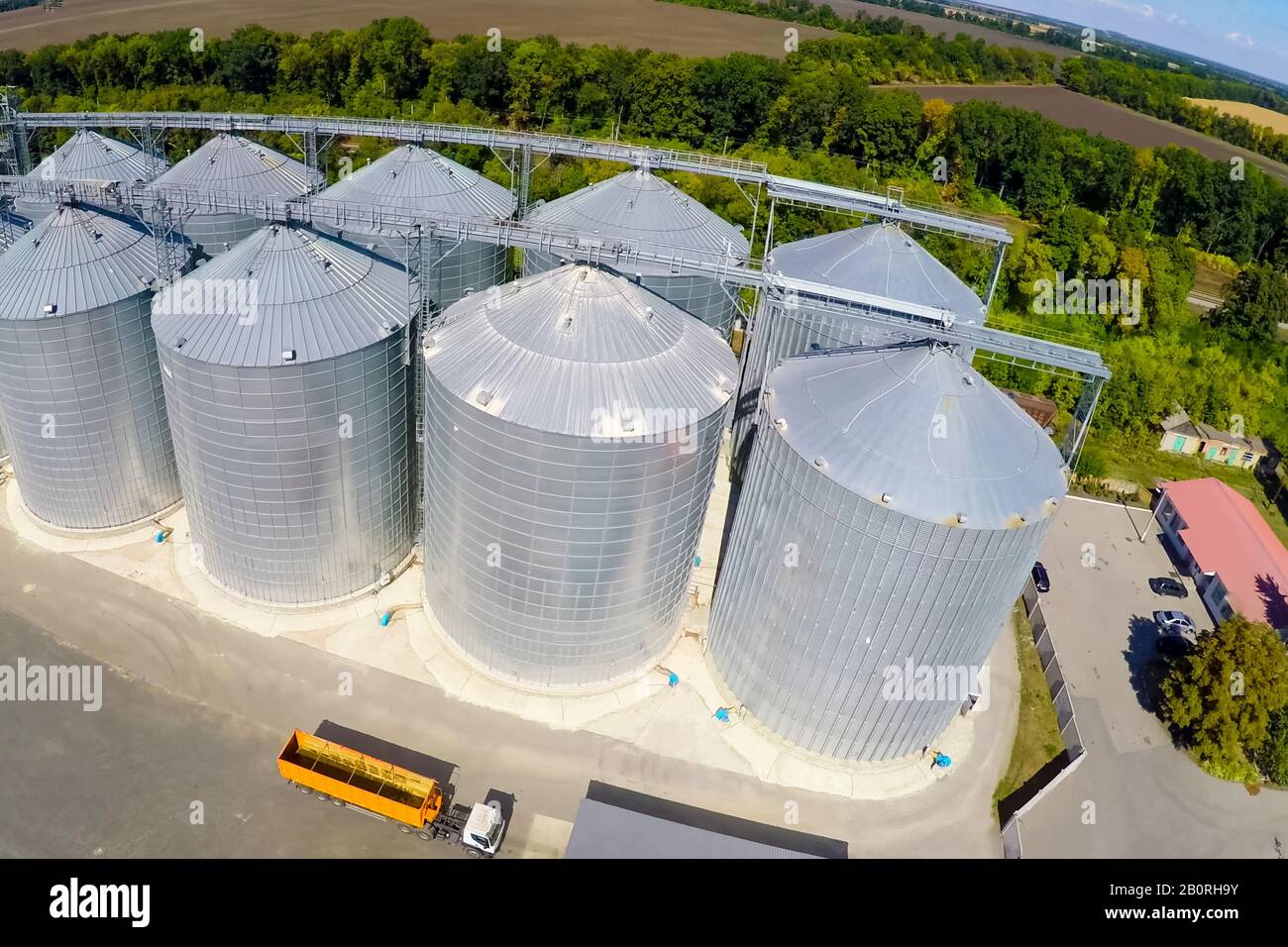 Flight of the grain terminal from the drone. The grain plant for storage and drying of grain. Grain terminal. Plant for the drying and storage Rice plant in the middle of fields. Stock Photo