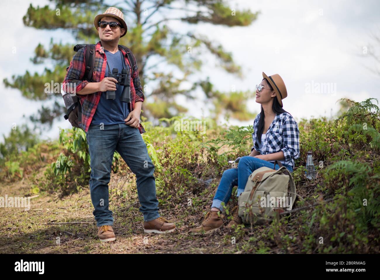 Thoughtful hiking couple looking away while relaxing in forest Stock Photo