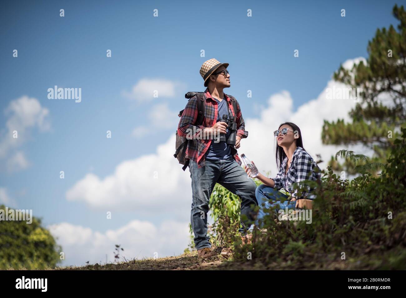 Thoughtful hiking couple looking away while relaxing in forest Stock Photo