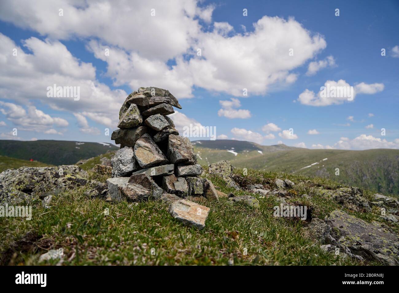 A small stone tower in mountainsin front od cloudly sky background Stock Photo