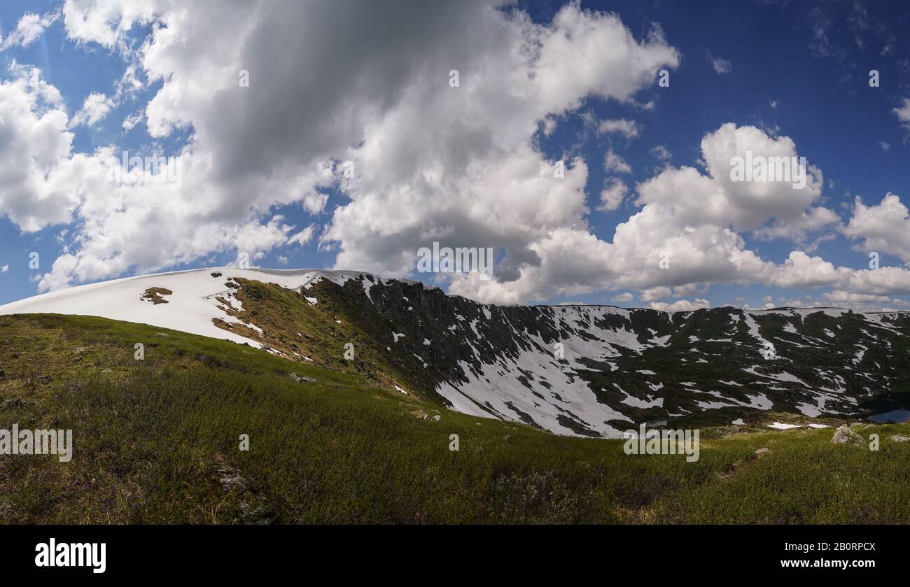 Snowbanks underlieing on the mountainside in Altay mountains and cloudly sky above it Stock Photo