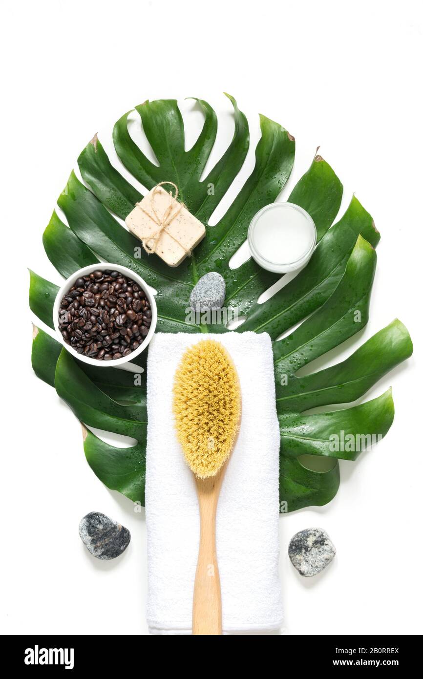 SPA set for cellulite removal, tough cacius brush, coffee beans, soap, towel, decorated monstera leaf, isolated on white. View from above. Vertical fo Stock Photo
