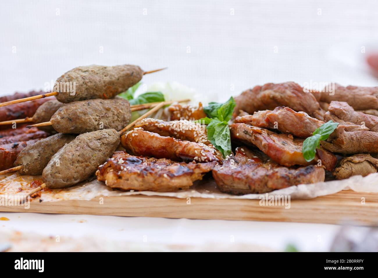 A front view of juicy meaty barbeque with lula kebabs on the wooden sticks and mint leafs as the toping Stock Photo