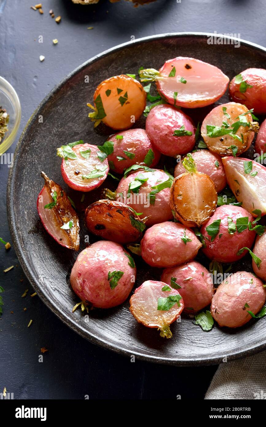 Close up of roasted radish on plate over dark plate. Vegetarian vegan food concept. Stock Photo