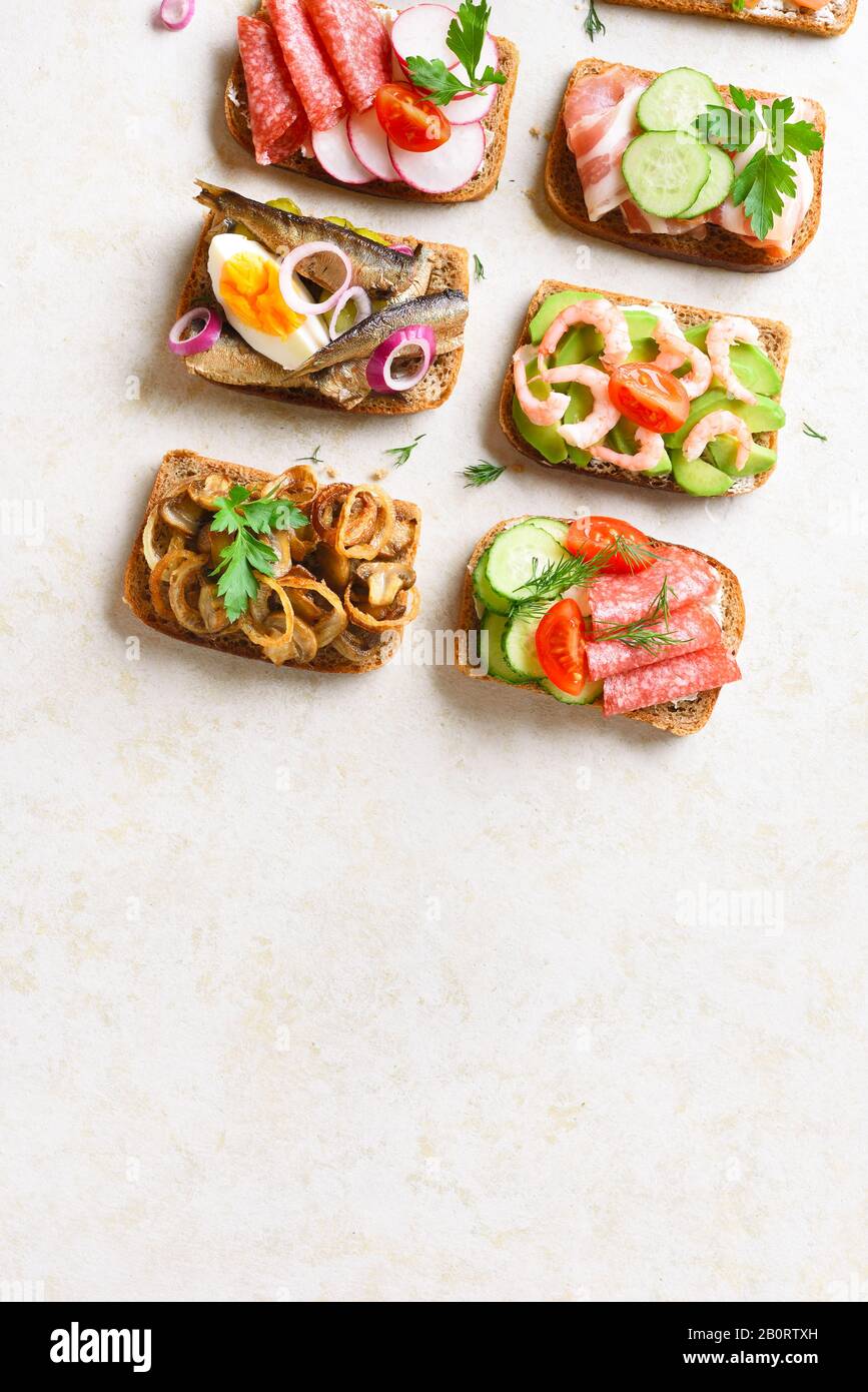 Set of different sandwiches with meat, vegetables, seafod. Assortment open sandwiches on light
