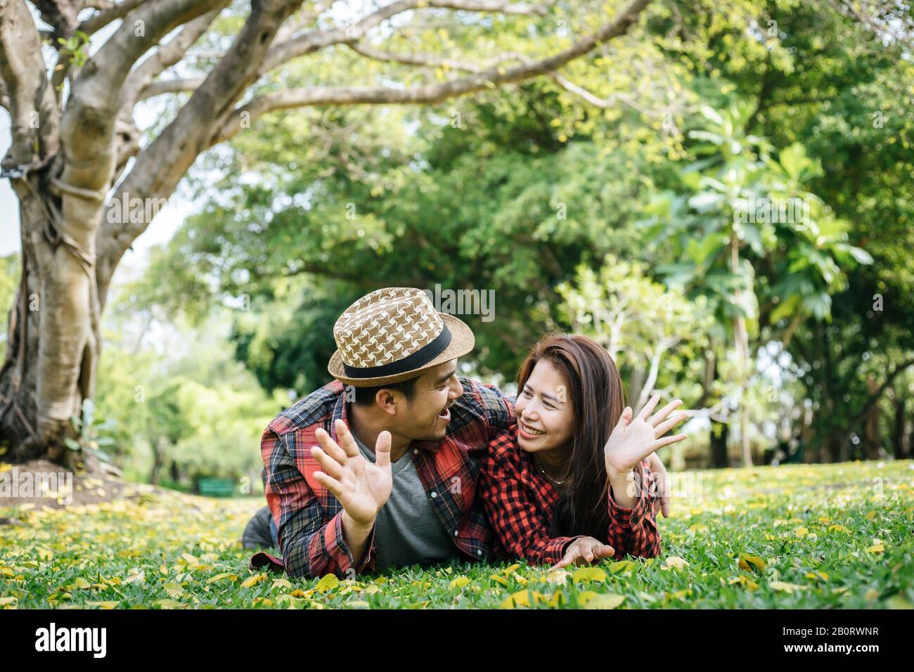 Romantic couple of young people lying on grass in park Stock Photo - Alamy