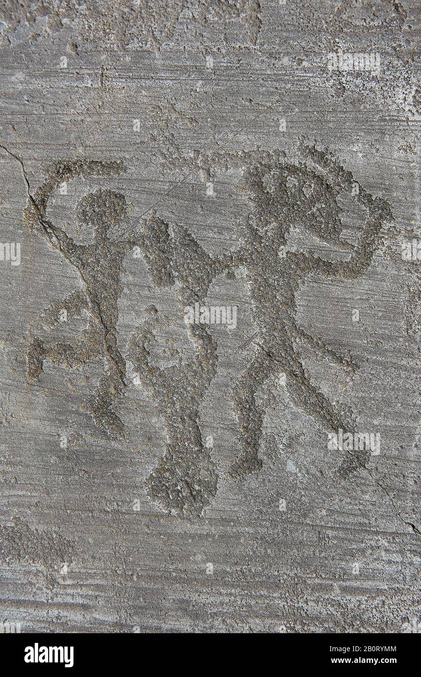 Petroglyph, rock carving, of two warriors fighting, the one on the right has a headress and they both have shields. Carved by the ancient Camunni peop Stock Photo