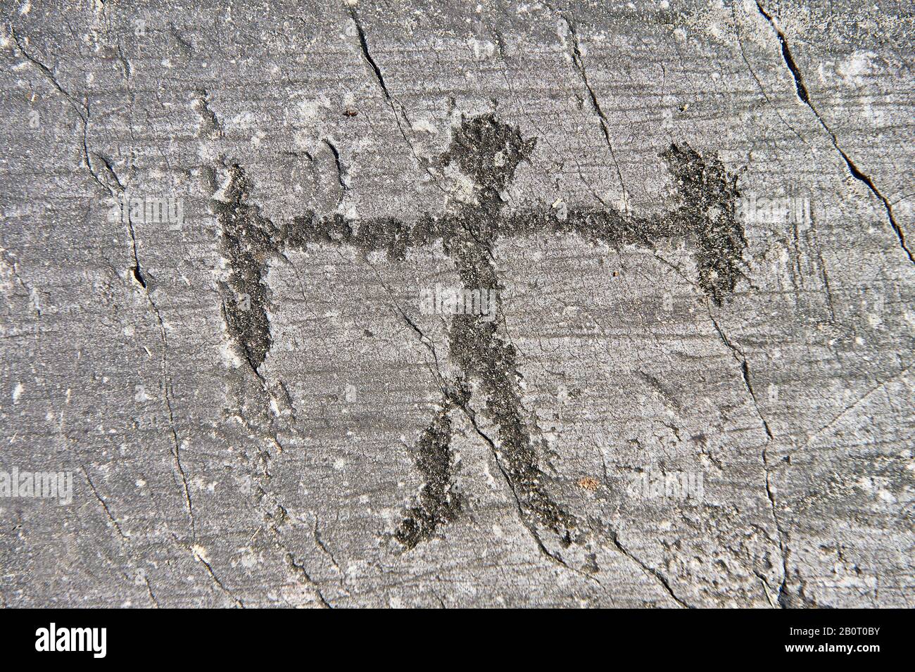 Petroglyph, rock carving, of schematic human figure with a sheilf and weapon. Carved by the ancient Camuni people in the Late Gopper Age between 2400 Stock Photo
