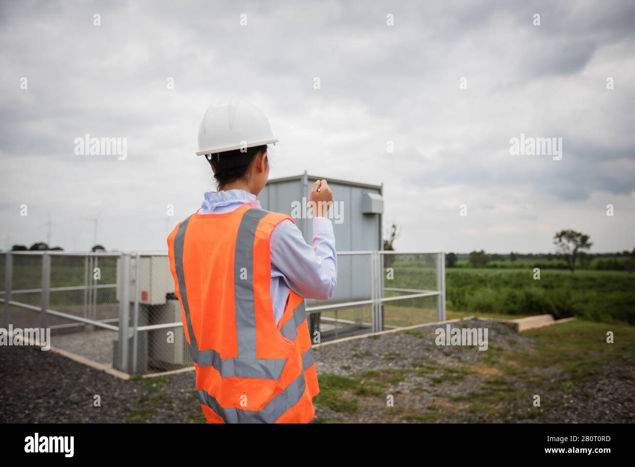 Asian engineer with hardhat using  tablet pc computer inspecting and working at wind turbine farm Power Generator Station Stock Photo
