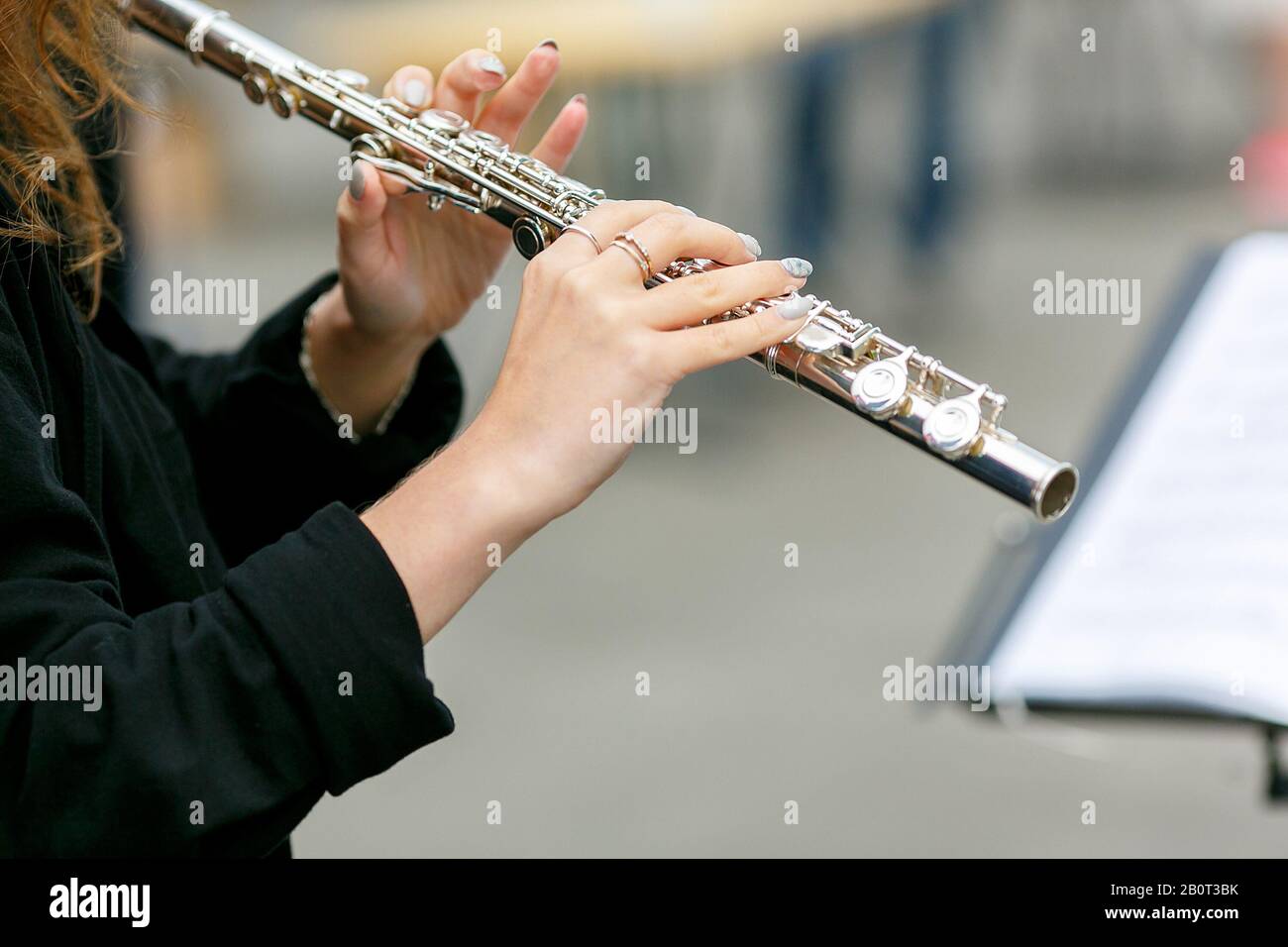 A closeup plane of street orchestra flautist with flute in her hands Stock Photo