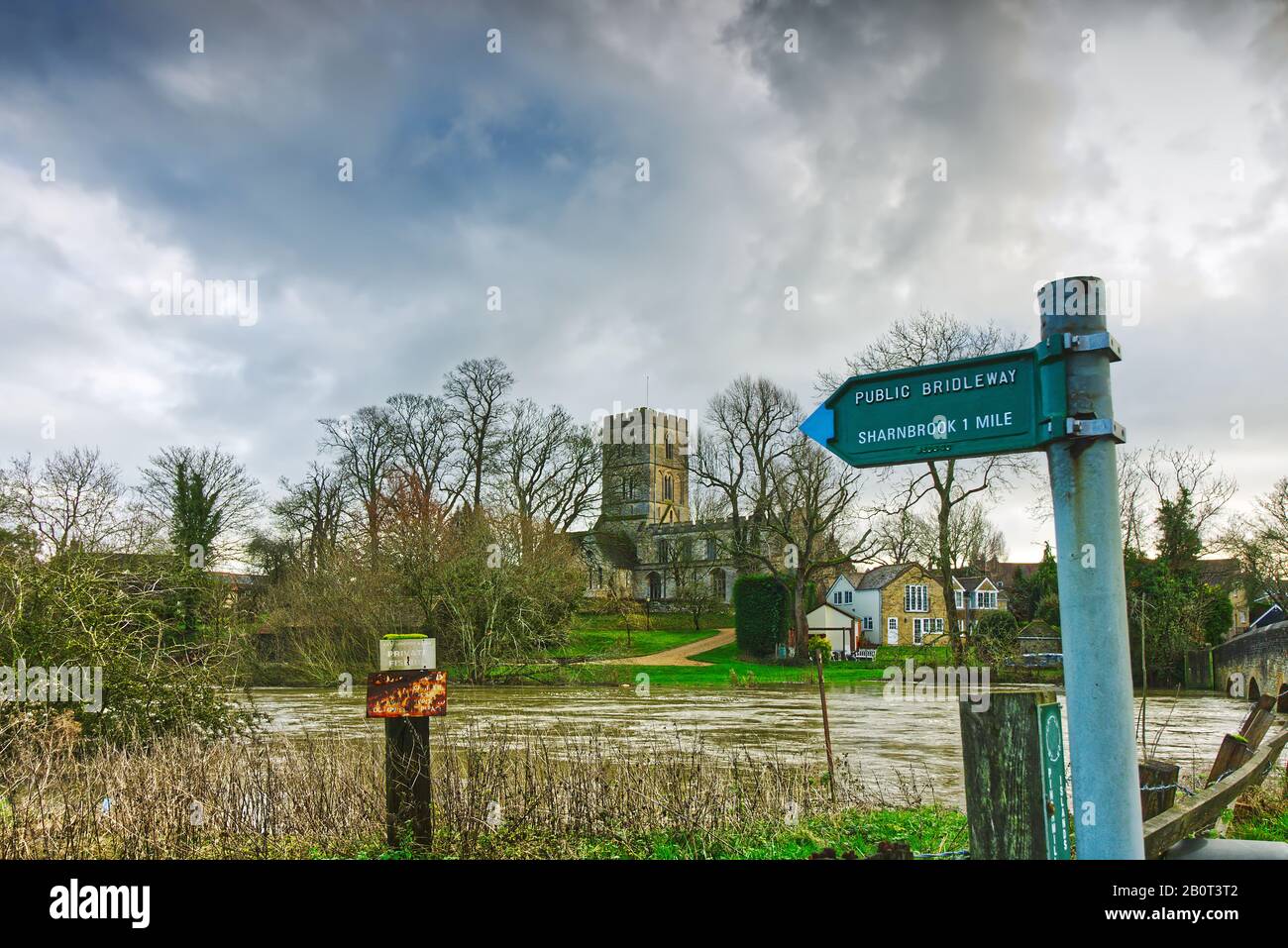 Signpost for public bridleway to Sharnbrook, Bedfordshire from Felmersham Bridge, with the River Great Ouse and St Mary's Church in the background Stock Photo