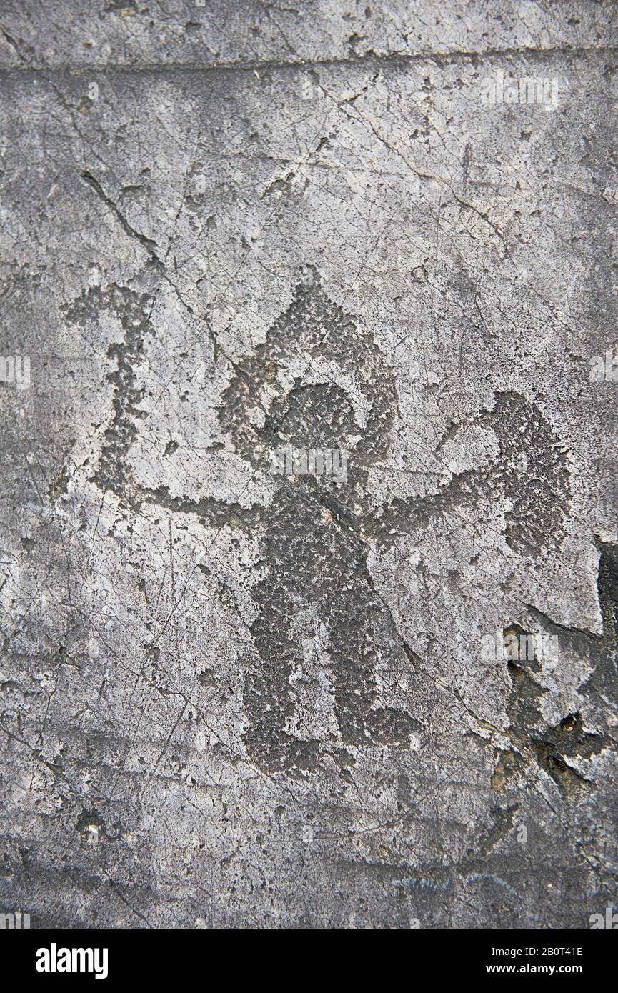Prehistoric Petroglyph, rock carving, of warrior with a halo type helmet small shield and axe carved by the Camunni people in the iron age between 100 Stock Photo