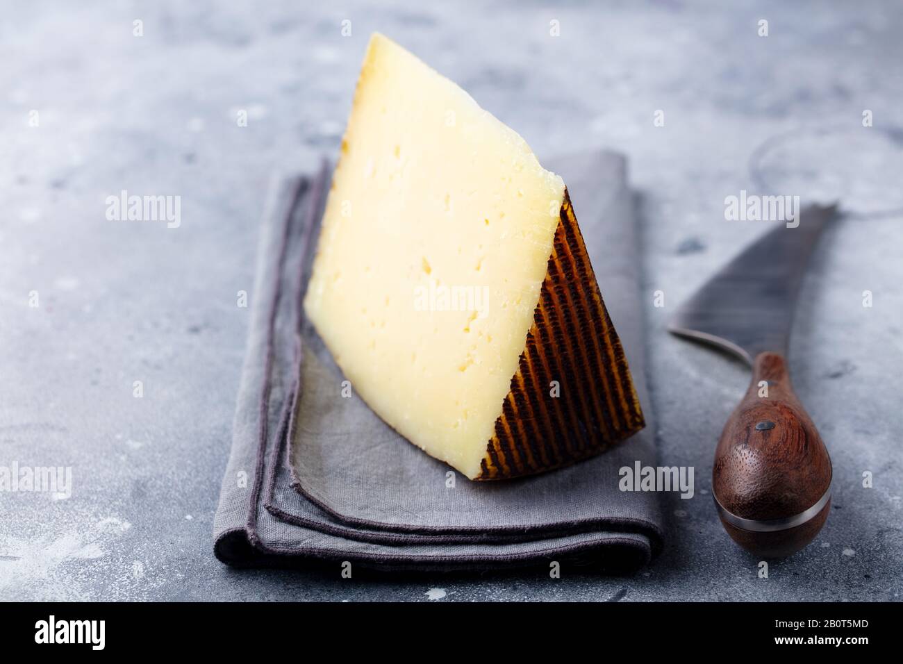 Hard cheese, Manchego with nuts on grey stone background. Close up. Stock Photo