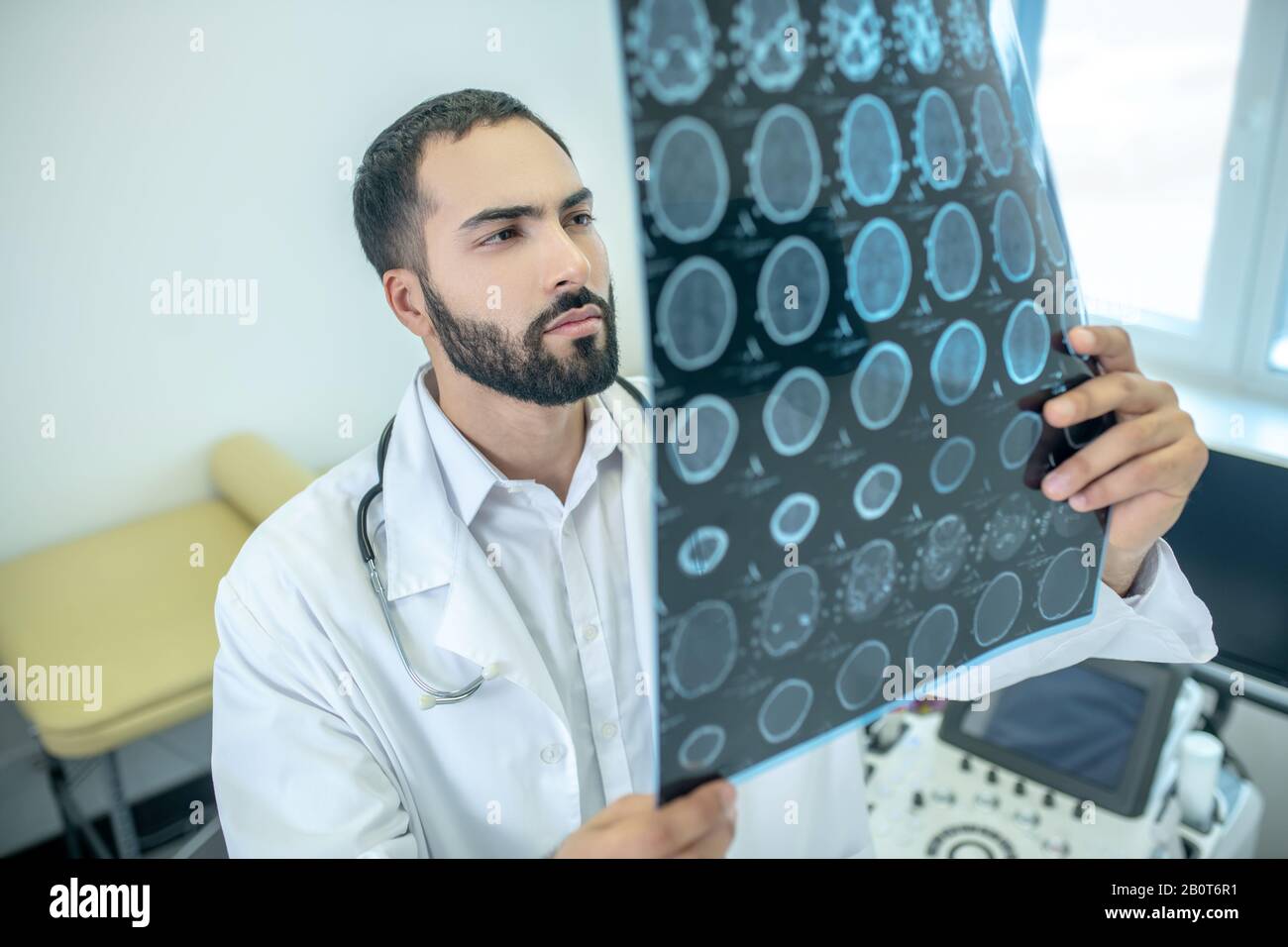 Male bearded doctor in a white robe analyzing MRI results Stock Photo