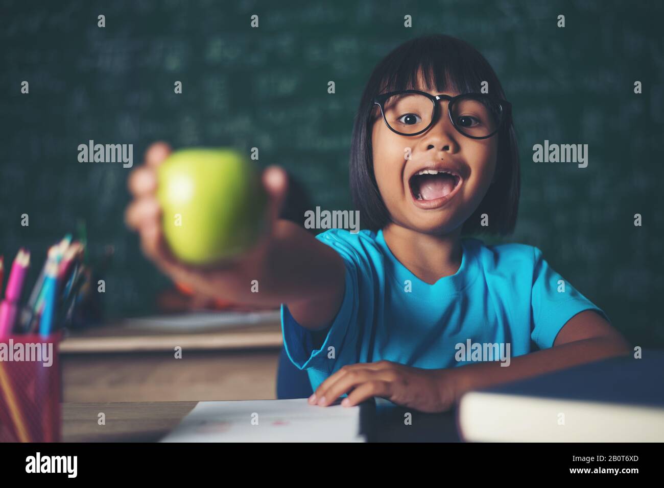 girl holding a apple in the classroom Stock Photo - Alamy