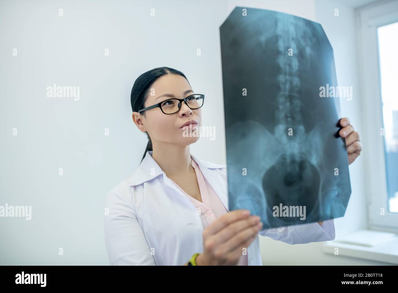 Dark-haired female doctor analyzing xray results of backbones Stock Photo