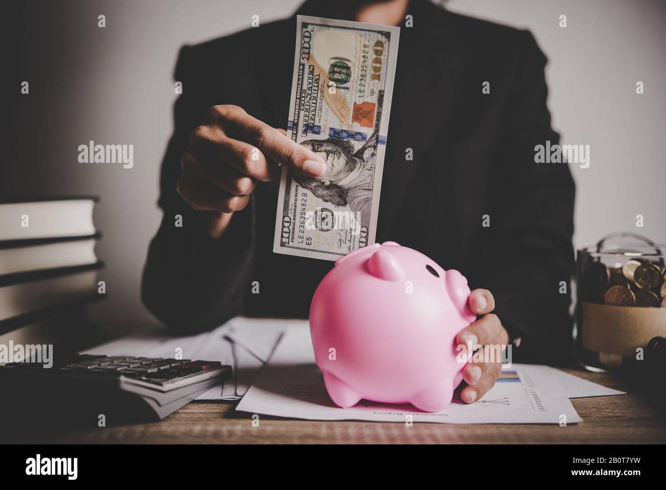 Woman putting euro banknote into a piggy bank on the table Stock Photo ...