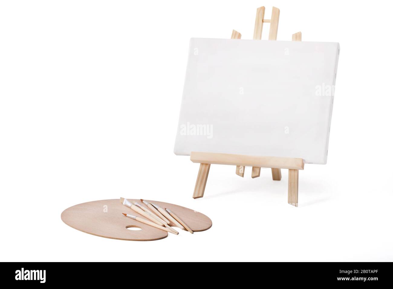 Small tripod with art canvas frame, wooden palette and new brushes isolated on white with working path. Stock Photo