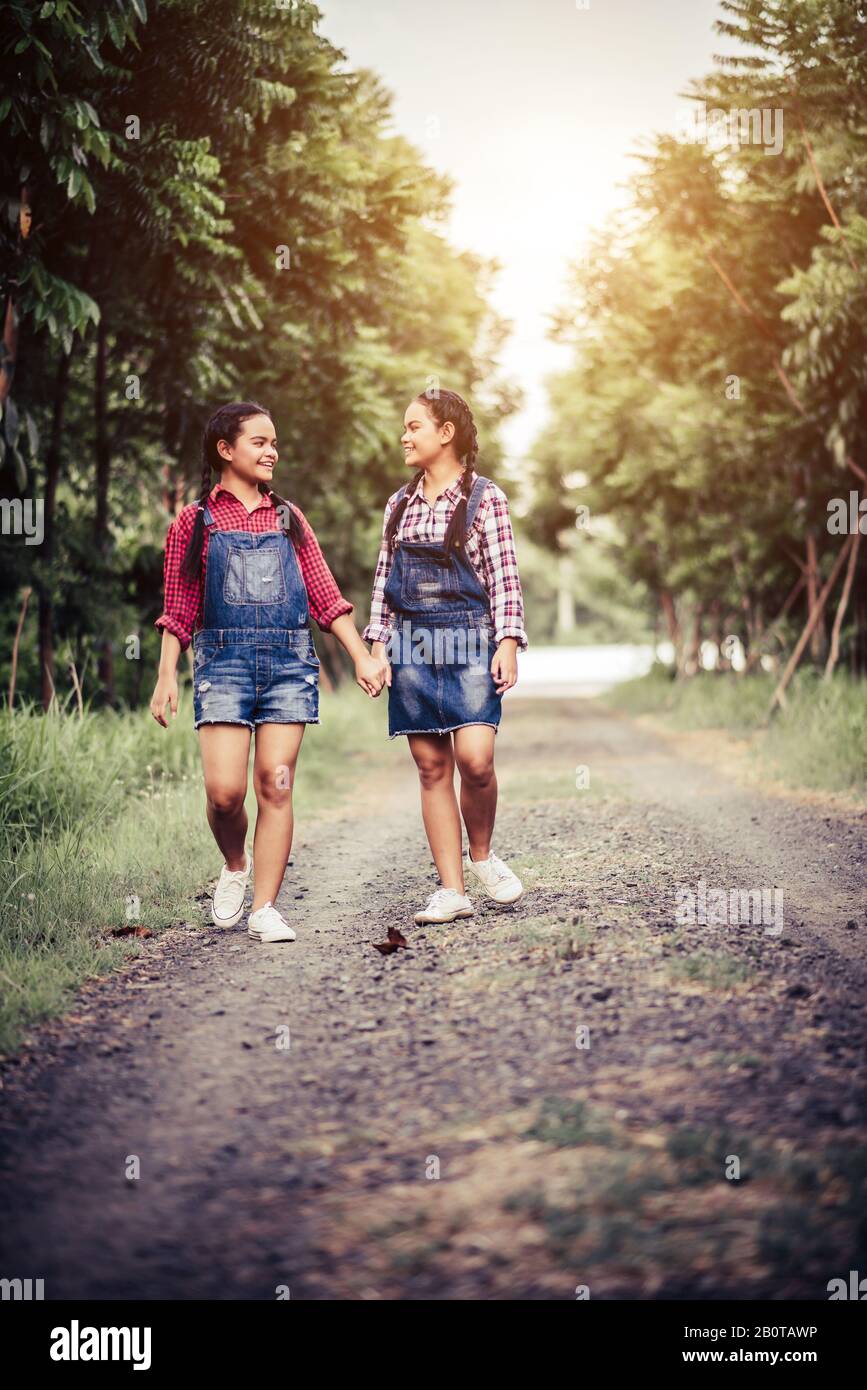 Two girls walking along a forest road Stock Photo - Alamy