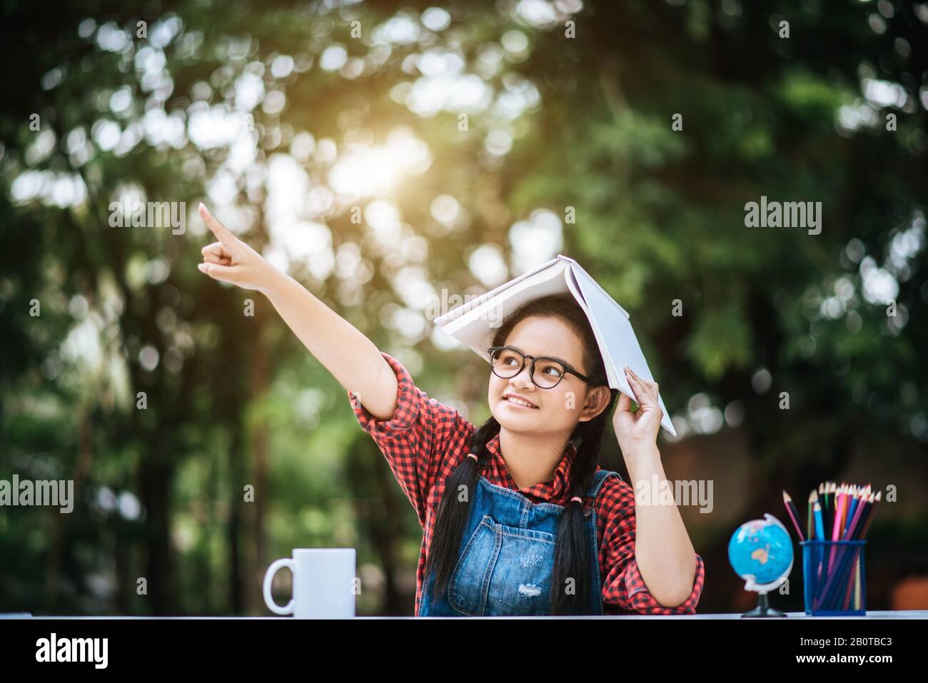 Child girl with book over her head in the park Stock Photo - Alamy
