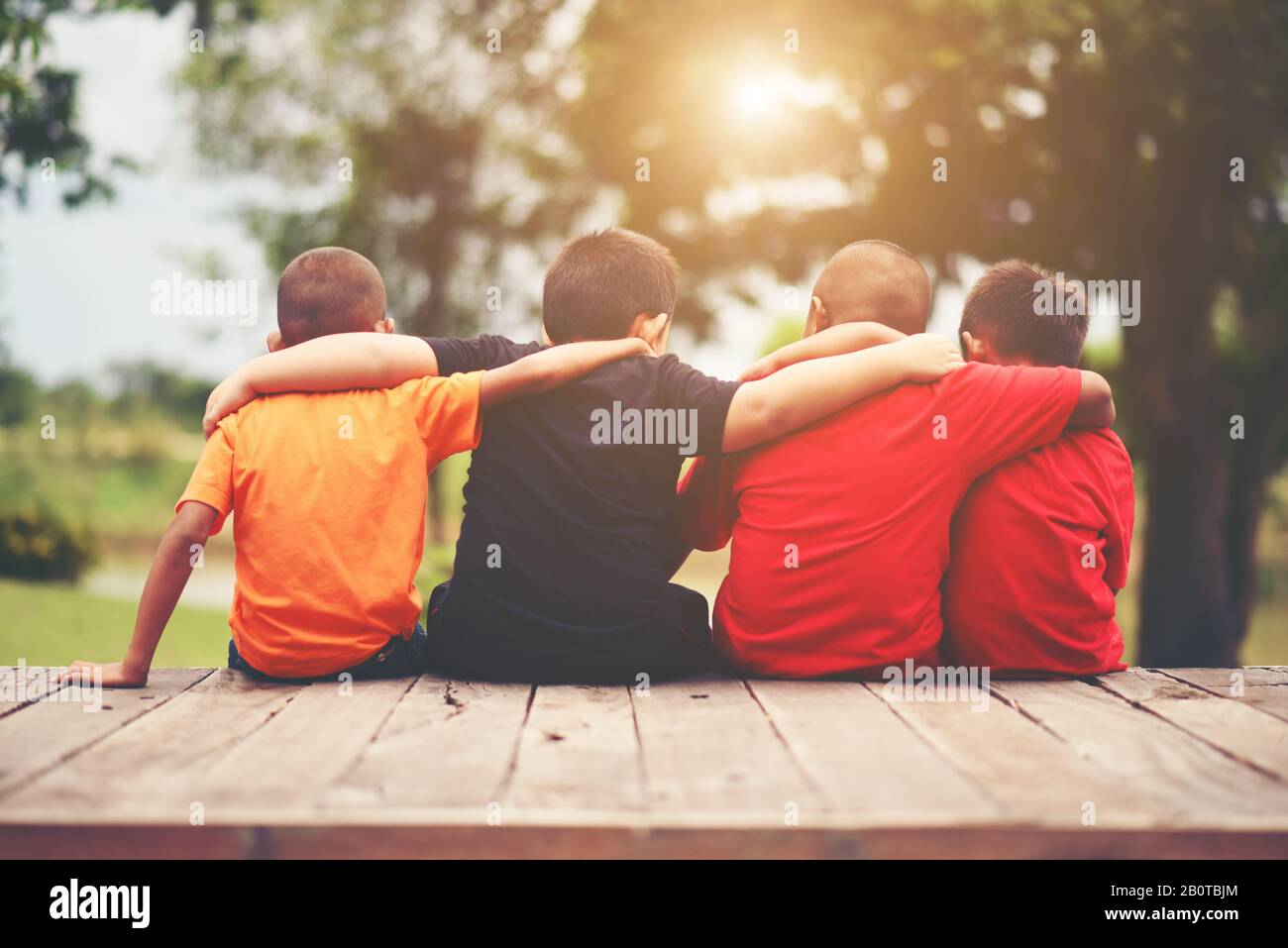 Group of kids friends arm around sitting together Stock Photo