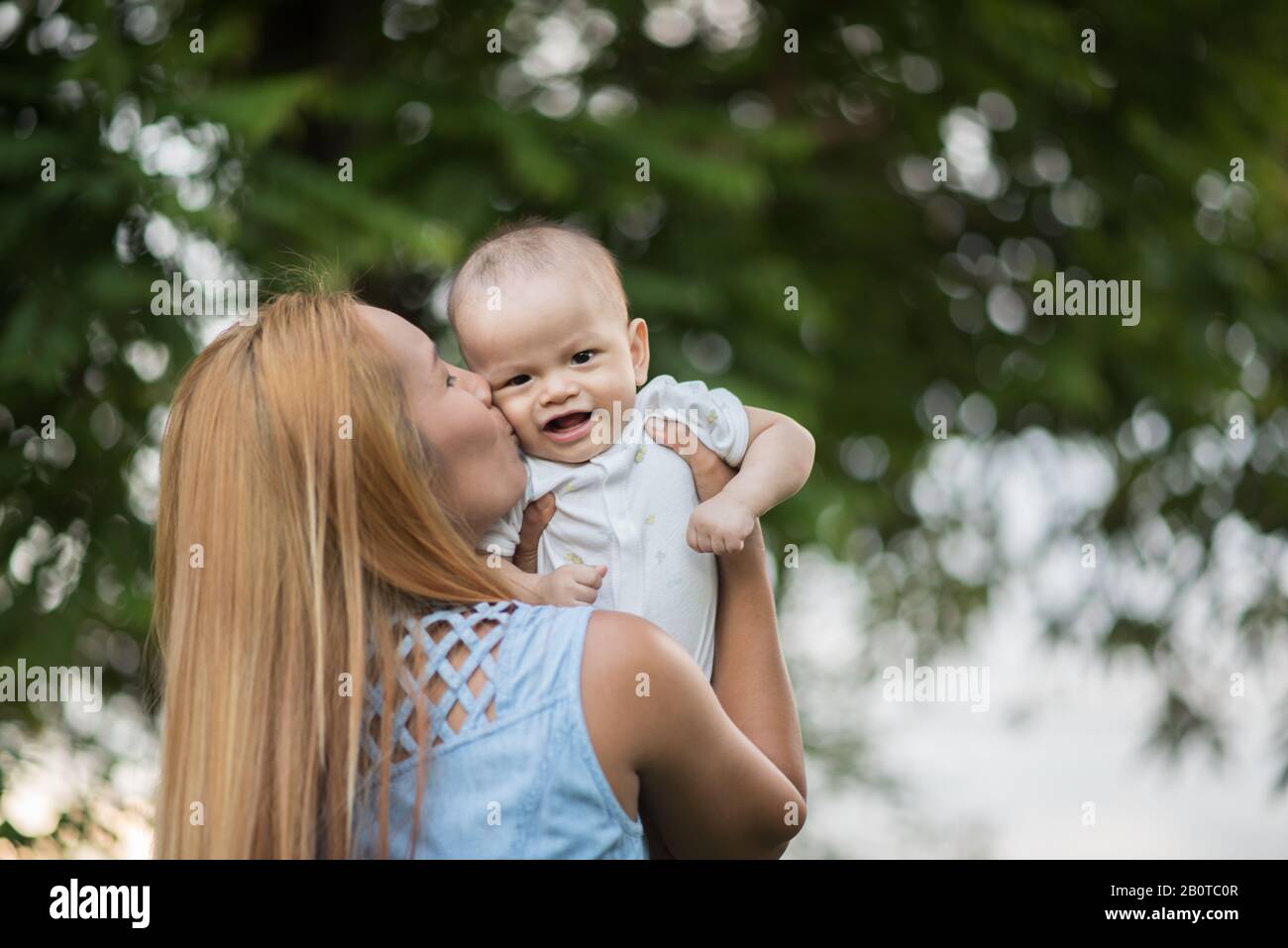 Mother throws baby up, laughing and playing in the park Stock Photo - Alamy