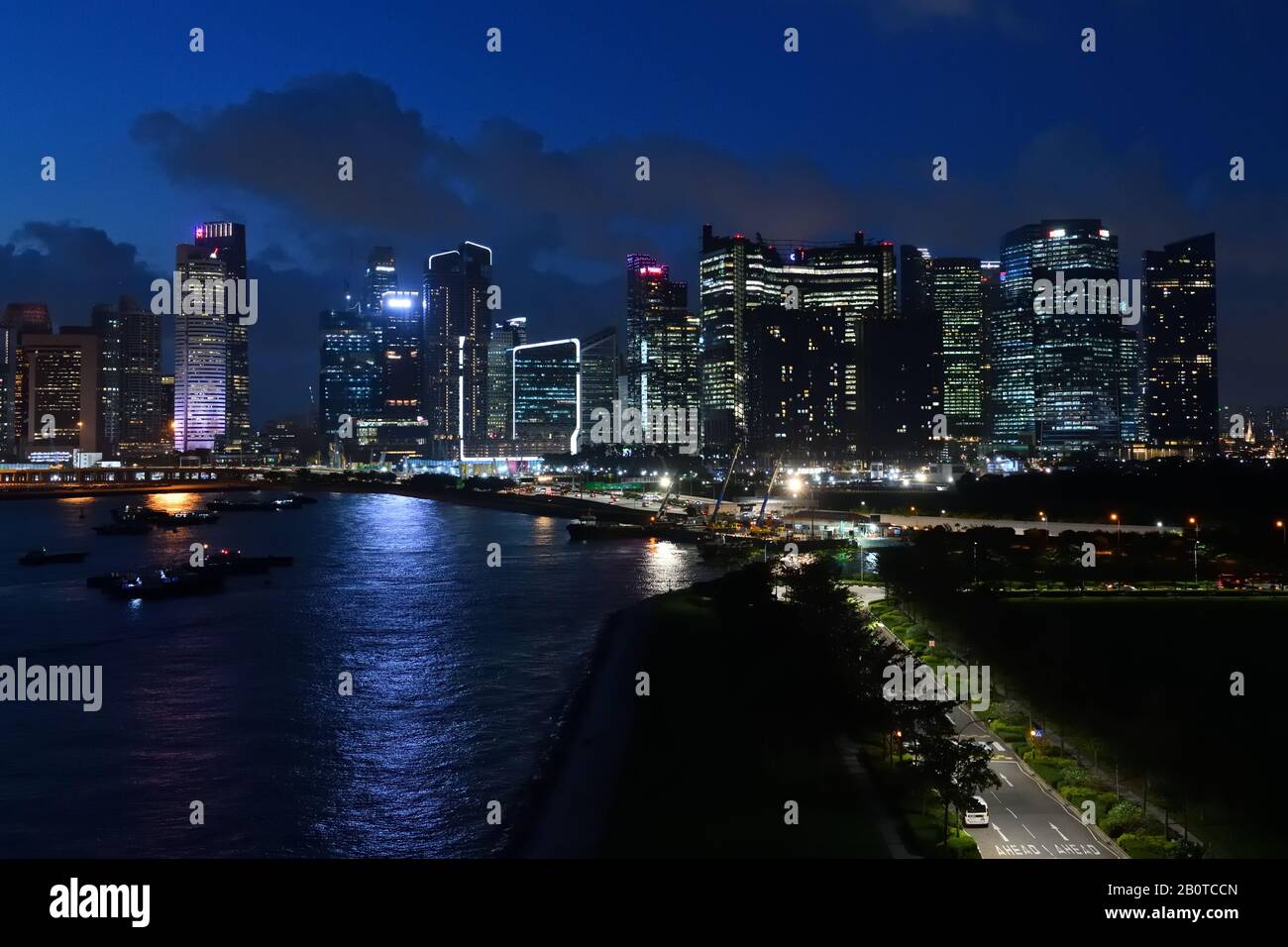 The Singapore city skyline begins to light up in fading light after sunset Stock Photo