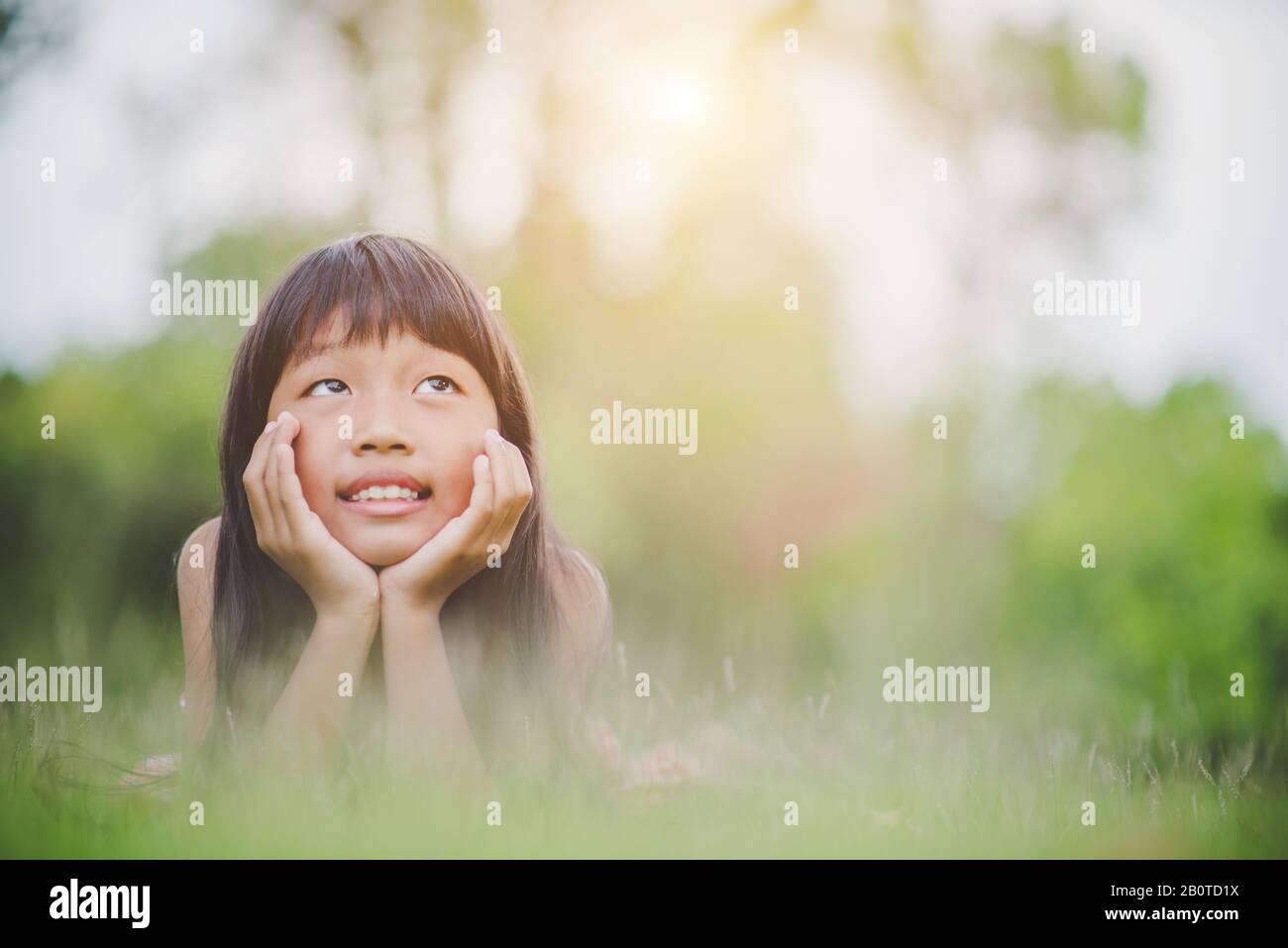 Little girl lying comfortably on the grass and smiling Stock Photo - Alamy