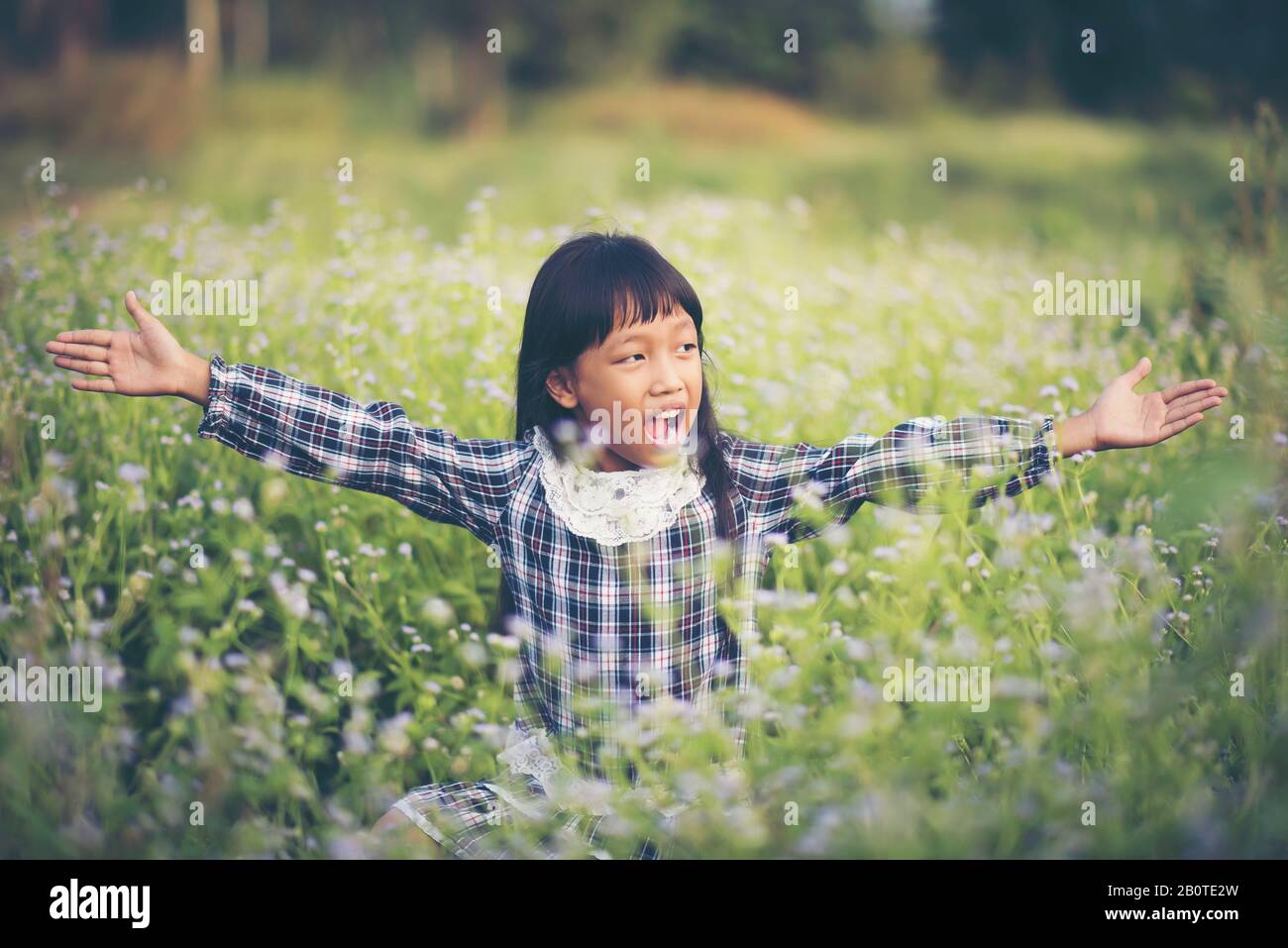 Happy girl sitting on the meadow Stock Photo - Alamy