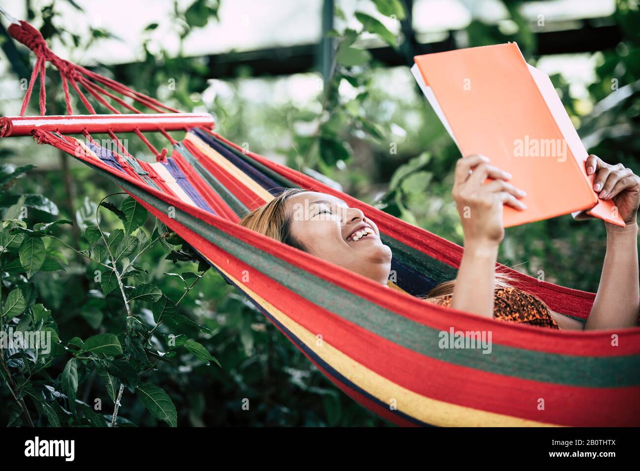 Young woman reading a book lying in a hammock Stock Photo - Alamy
