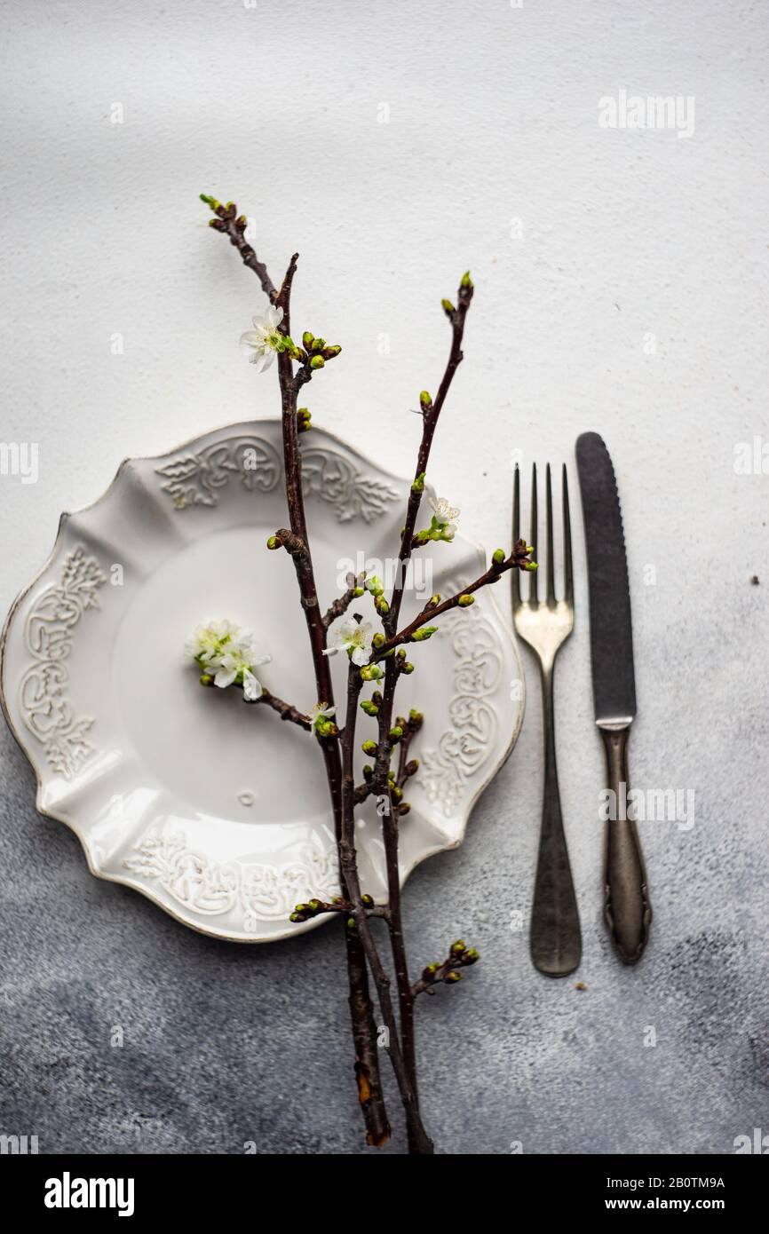 Spring table setting with cutlery and blooming cherry branch on rustic background with copy space Stock Photo