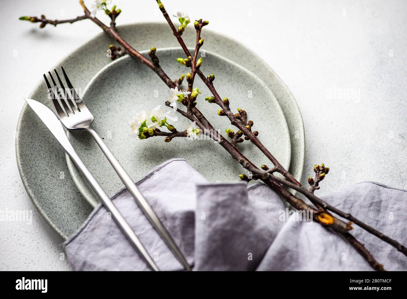 Spring table setting with cutlery and blooming cherry branch on rustic background with copy space Stock Photo