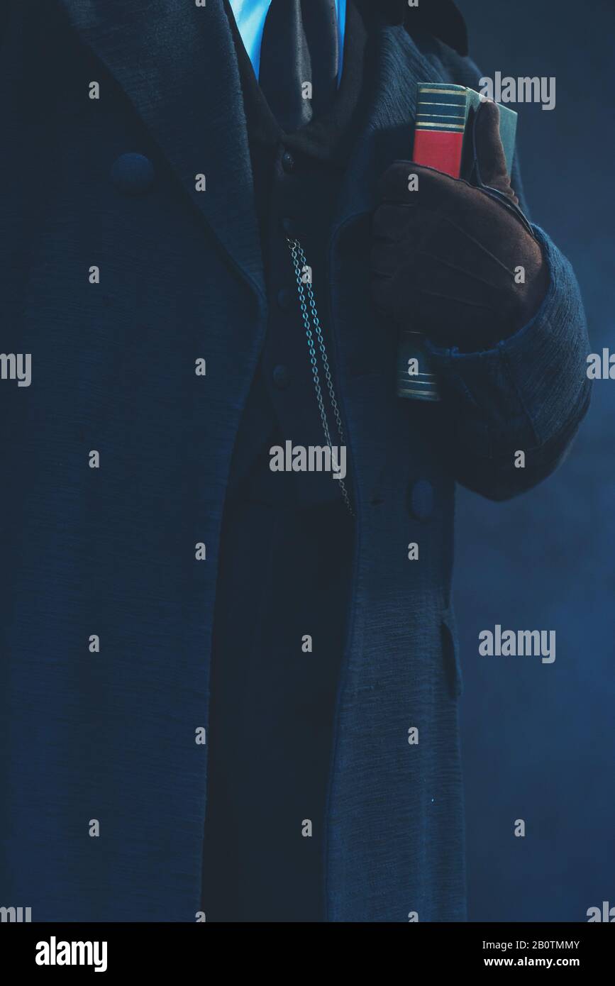 Edwardian man in long black coat and gloves holding book Stock Photo
