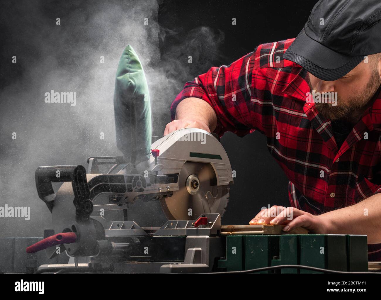 Closeup of young man sawing lumber with sliding compound miter saw