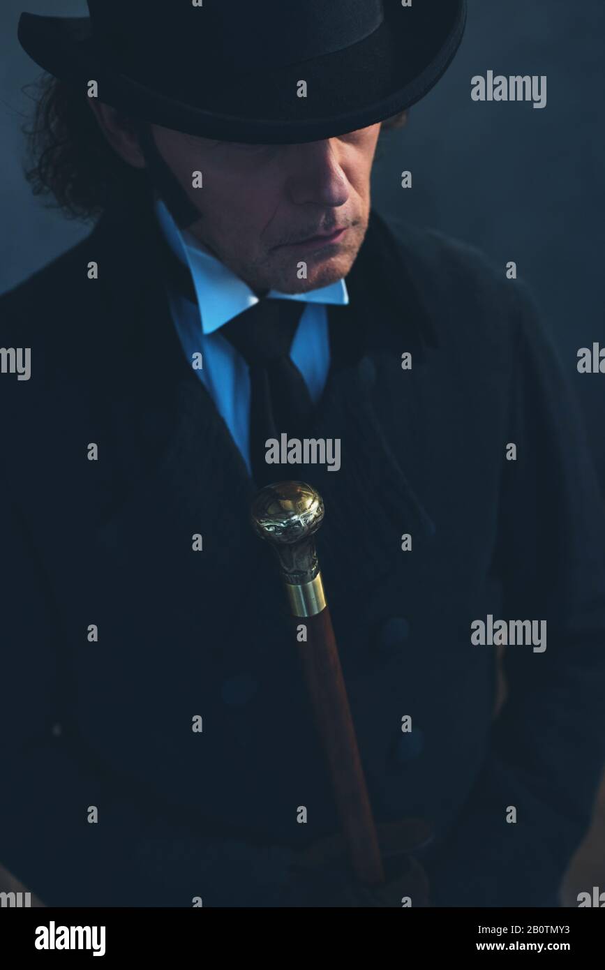 Edwardian man in long black coat and hat holding cane Stock Photo Alamy