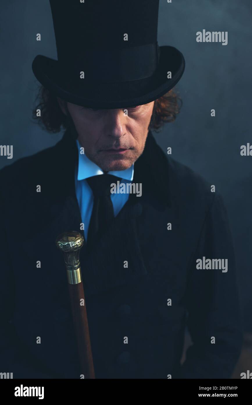 Edwardian man in long black coat and hat holding cane Stock Photo Alamy