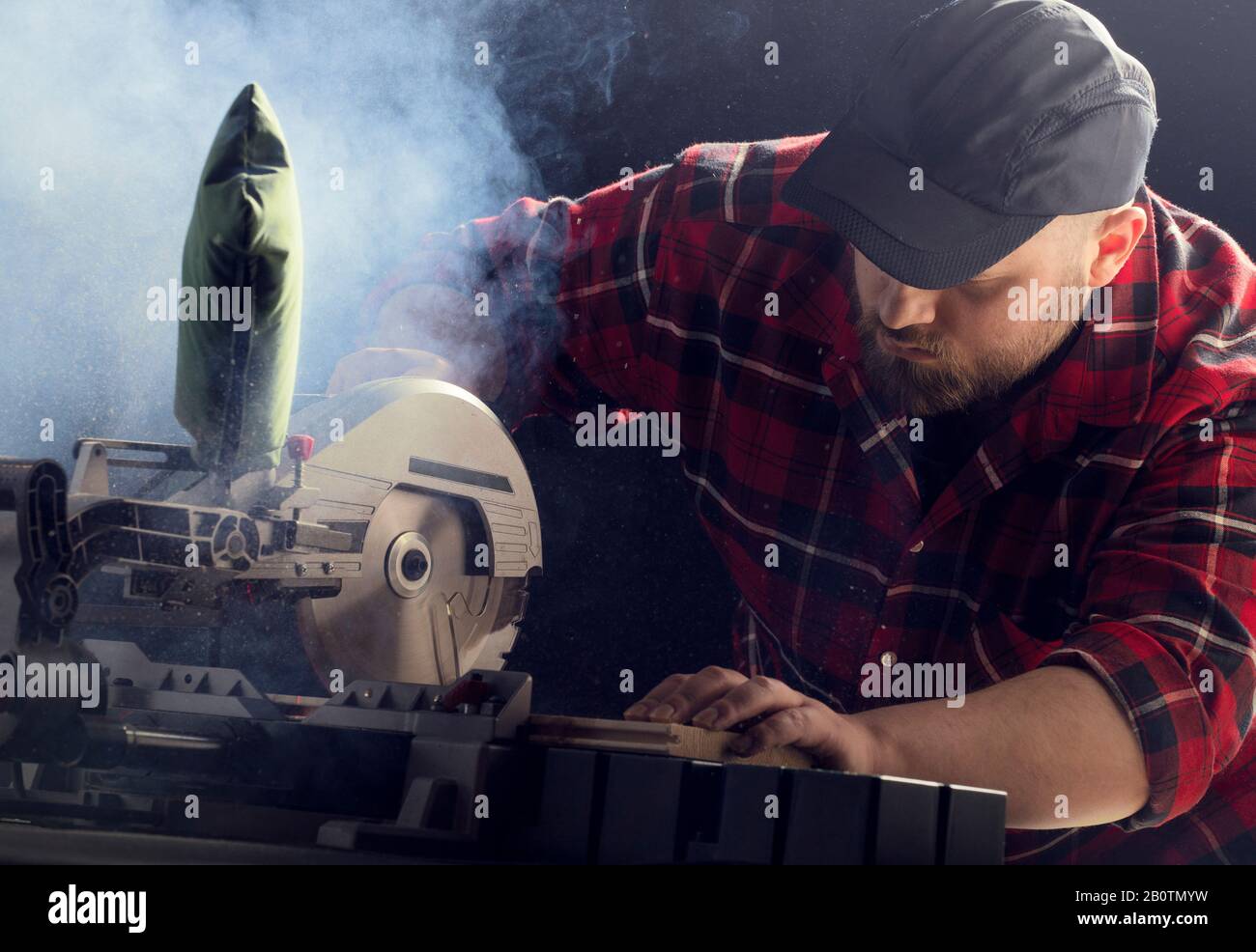 Closeup of young man sawing lumber with sliding compound miter saw