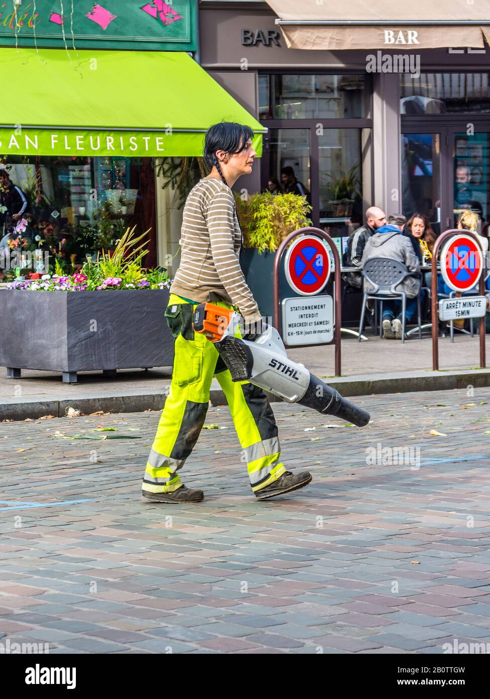 Young woman council worker cleaning the street after market day - Loches;, Indre-et-Loire, France. Stock Photo