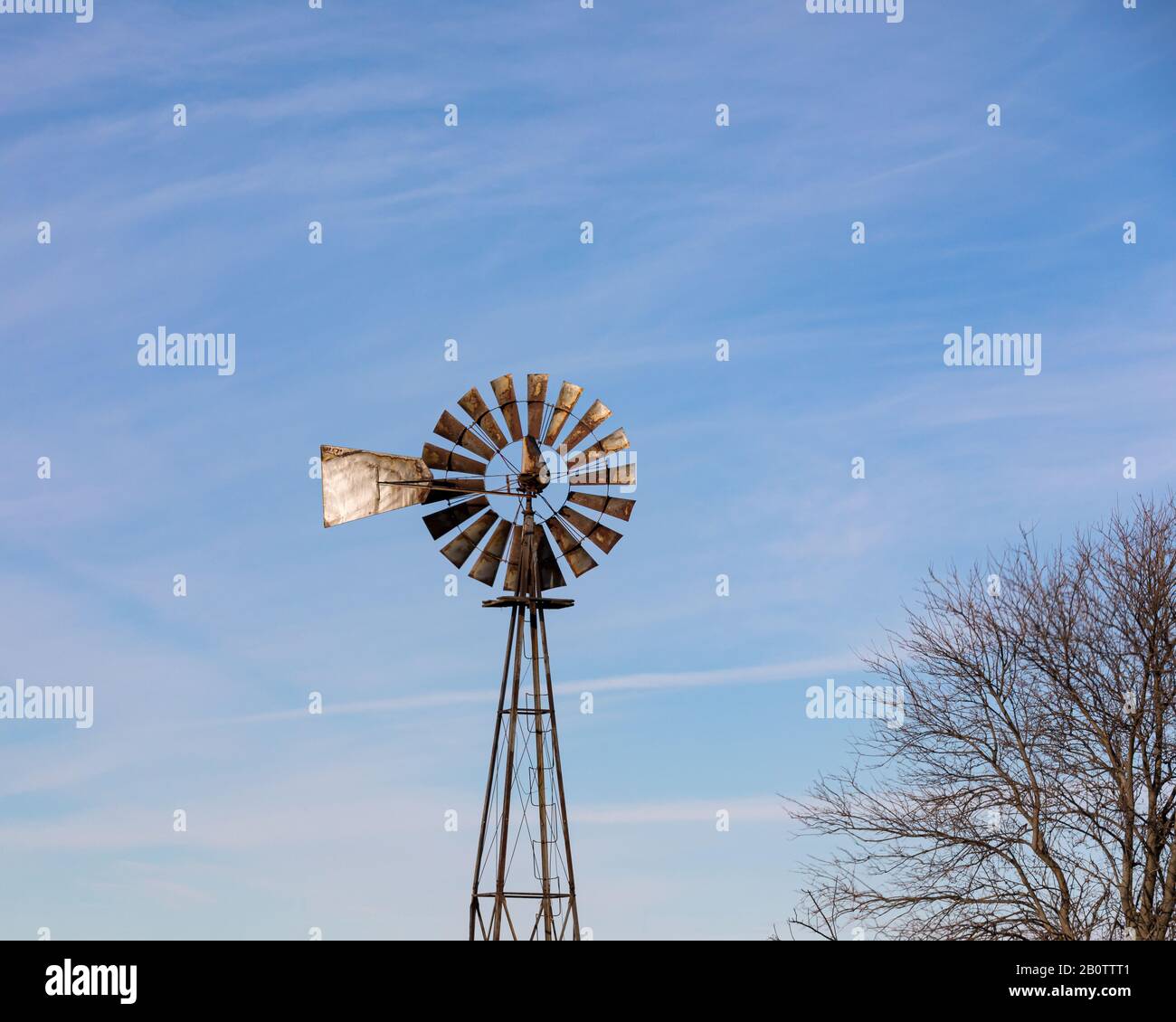 Old, antique windmill, wind pump, with rusty blades, vanes or sails on Midwest farm Stock Photo