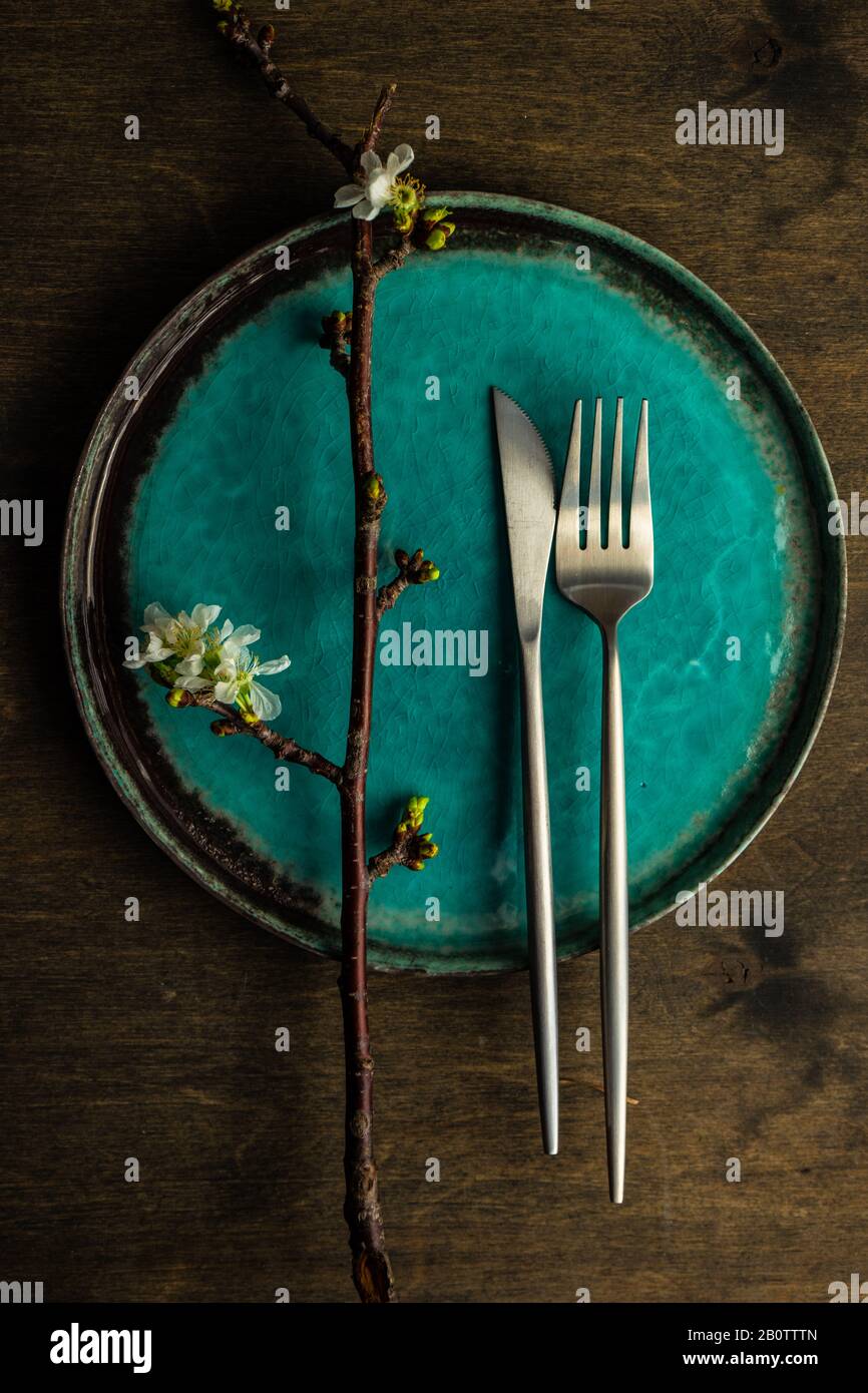 Spring table setting with cutlery and blooming cherry branch on rustic background with copy space Stock Photo