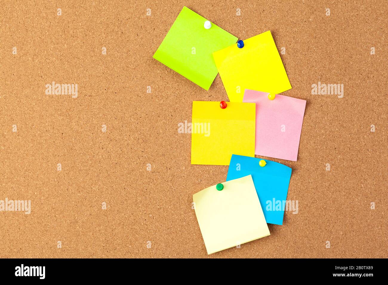 Cork board with several colorful blank notes with pins Stock Photo