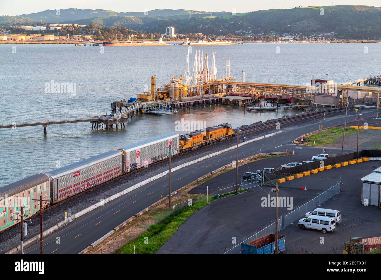 Benicia California, industrious like a soothing chanter without noise, a freight train hums in mechanical rhythm whilst the tops of the hillside are l Stock Photo