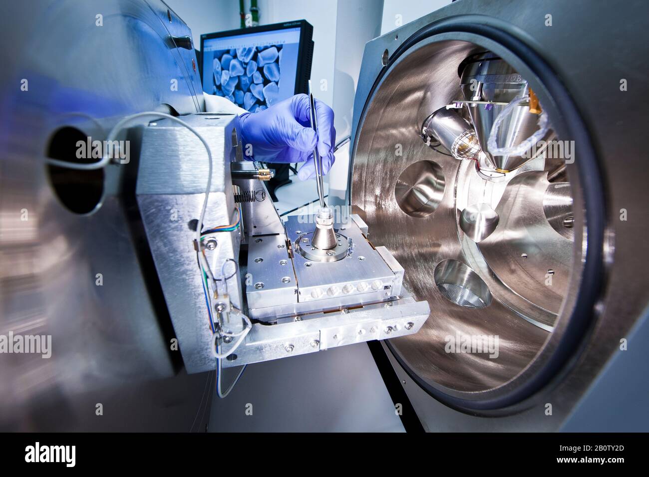 A scientist with tweezers in his hand using scanning electronic microscope Stock Photo