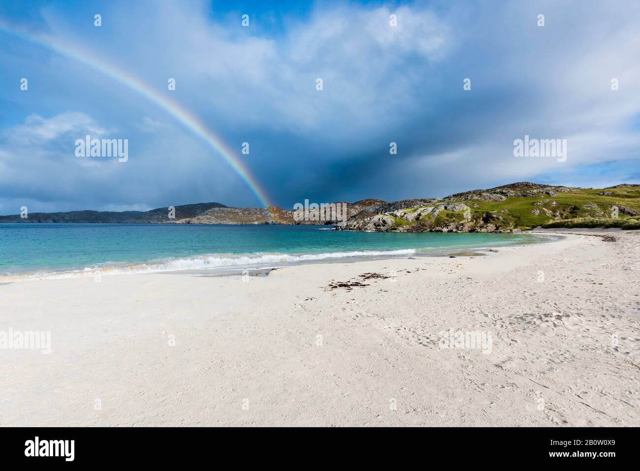 Rainbow over remote empty Achmelvich beach on the shore of Achmelvich Bay in Assynt, Sutherland in the North West Scottish Highlands Stock Photo