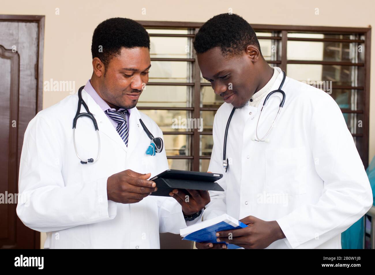 young doctors standing and sharing techniques of working on a tablet. Stock Photo